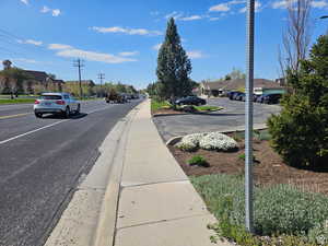View of asphalt road featuring curbs, sidewalks, a residential view, and street lighting