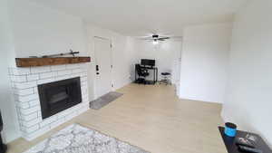 Living area featuring wood finished floors, a ceiling fan, an office area, and a fireplace