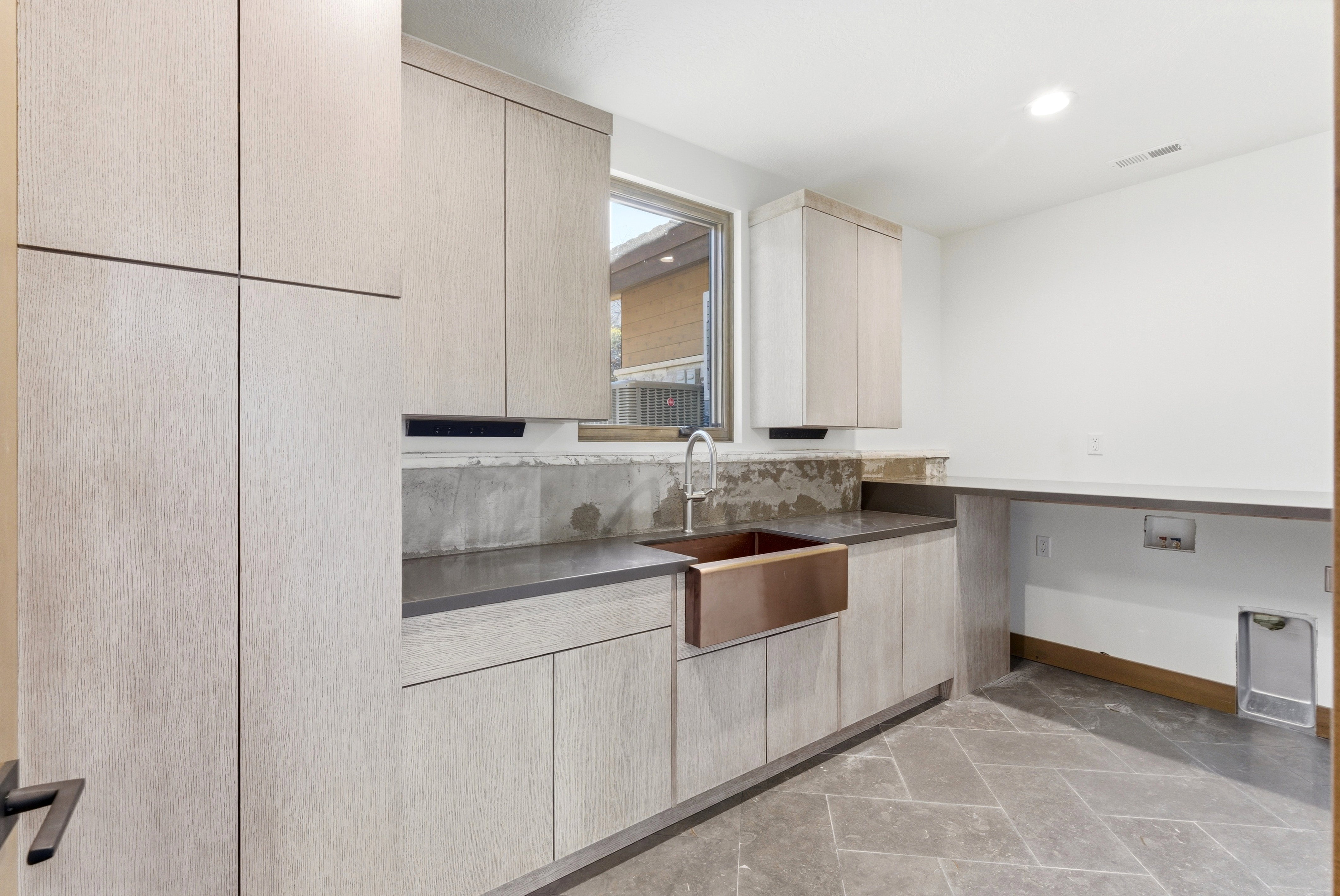 Kitchen featuring light wood finish cabinets, modern cabinets, recessed lighting, and dark countertops