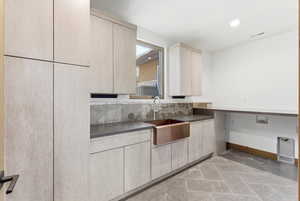 Kitchen featuring light wood finish cabinets, modern cabinets, recessed lighting, and dark countertops