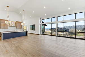 Unfurnished living room featuring light wood finished floors, lofted ceiling, a mountain view, and recessed lighting