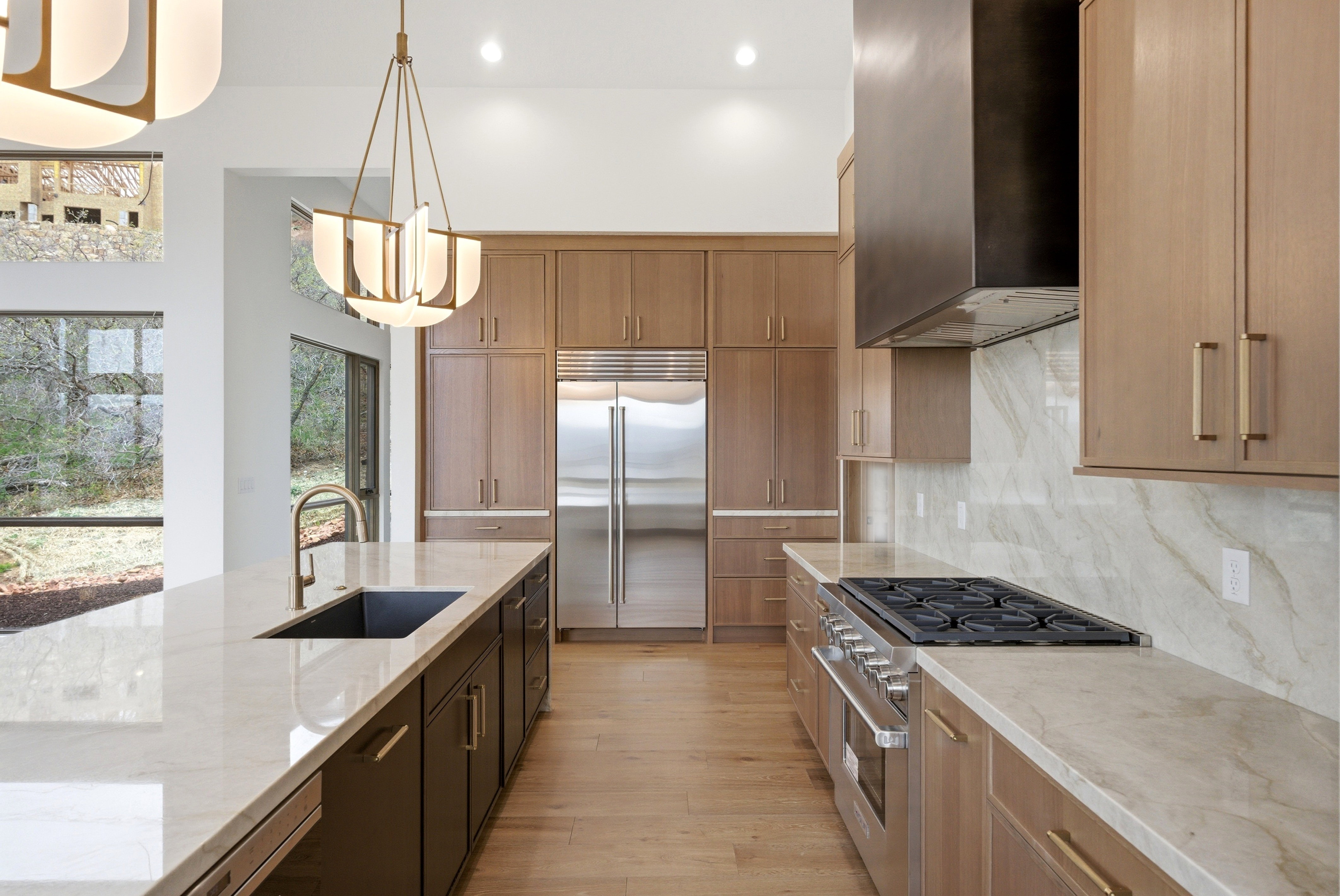 Contemporary kitchen featuring light wood-finish cabinetry, a large center island with an undermount sink, and light-toned countertops