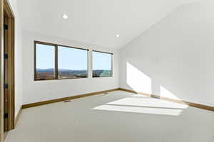 Unfurnished room with light colored carpet, lofted ceiling, and a mountain view