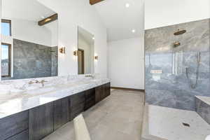 Full bath with a marble finish shower, double vanity, beam ceiling, and light tile patterned flooring