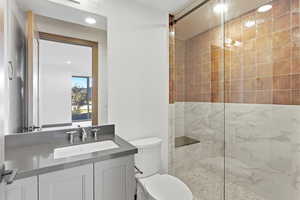 Bathroom with a marble finish shower, vanity, and recessed lighting