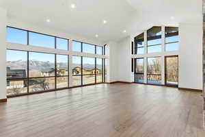 Unfurnished living room with a high ceiling, light wood finished floors, recessed lighting, and a mountain view