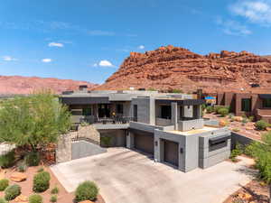 View of front of house featuring driveway, a mountain view, an attached garage, stucco siding, and a balcony