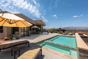 View of pool featuring a mountain view, a patio area, a pool with connected hot tub, and outdoor dining area