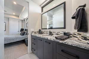 Ensuite bathroom with vanity, decorative backsplash, recessed lighting, and tile patterned flooring