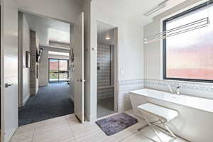 Full bathroom featuring a soaking tub, a stall shower, tile patterned flooring, and tile walls