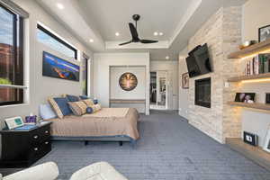 Carpeted bedroom with a glass covered fireplace, recessed lighting, a raised ceiling, and ceiling fan