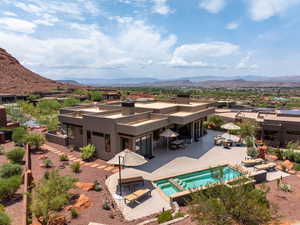 Rear view of house with a mountain view, a patio area, stucco siding, a balcony, and a pool with connected hot tub