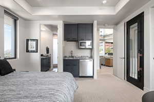 Bedroom featuring light colored carpet and a tray ceiling