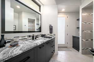 Full bath with vanity, backsplash, tile patterned flooring, recessed lighting, and a shower