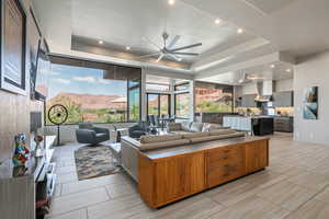 Living area with a ceiling fan, a raised ceiling, and recessed lighting