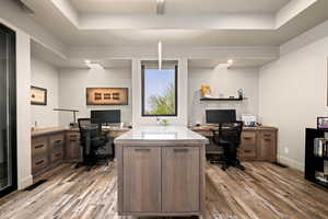 Home office with dark wood-type flooring and a raised ceiling