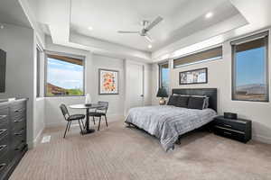 Carpeted bedroom with a raised ceiling, ceiling fan, and recessed lighting