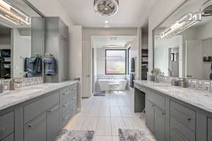 Full bath with two vanities, a soaking tub, backsplash, and tile patterned floors