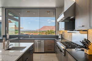Kitchen with exhaust hood, appliances with stainless steel finishes, dark stone counters, and backsplash