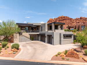 View of front of property with concrete driveway, stucco siding, an attached garage, and a balcony