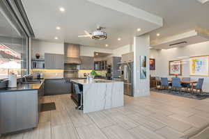 Kitchen with open shelves, tasteful backsplash, high end fridge, a center island with sink, and dark stone counters