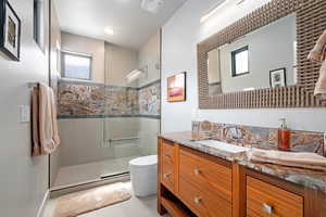Full bath with healthy amount of natural light, vanity, a tile shower, and tile patterned flooring