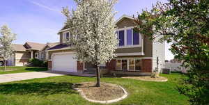 View of front facade with brick siding, driveway, and an attached garage