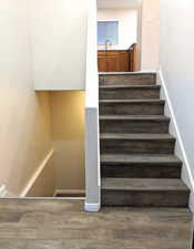 Staircase with wood finished floors and baseboards