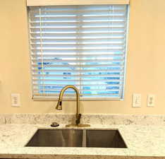Kitchen view of a sink and light stone counters