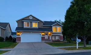 View of front facade with brick siding, concrete driveway, a front yard, and stucco siding