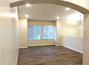 Unfurnished room with dark wood-type flooring, recessed lighting, and arched walkways