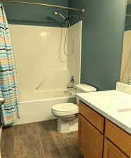 Full bathroom with vanity, wood finished floors, and shower / bath combo with shower curtain