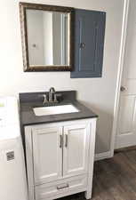 Bathroom featuring washer / dryer, vanity, wood finished floors, and electric panel