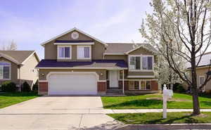 View of front of home with brick siding, an attached garage, driveway, and a front lawn