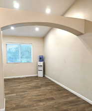 Spare room with arched walkways, dark wood-type flooring, and recessed lighting