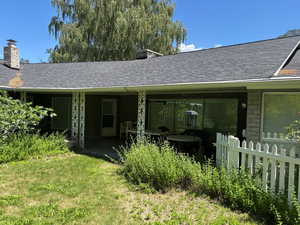 Back of property with a chimney, a shingled roof, and stone siding
