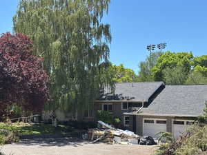 View of front of house featuring a garage, roof with shingles, and brick siding