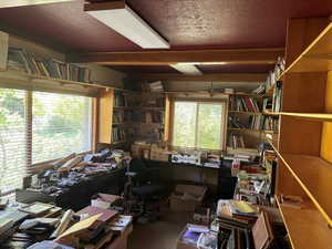 Carpeted home office with a textured ceiling and beam ceiling