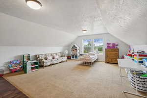 Bedroom featuring a textured ceiling, lofted ceiling, and wood finished floors