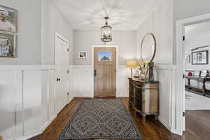Entrance foyer featuring wood finished floors, a chandelier, wainscoting, and a decorative wall