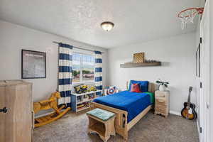 Carpeted bedroom with a textured ceiling and baseboards