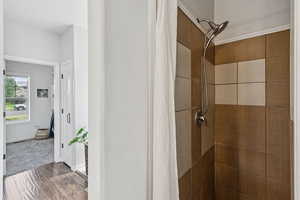 Bathroom featuring tiled shower and wood finished floors