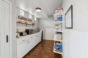 Bar area with dark wood finished floors and stainless steel microwave