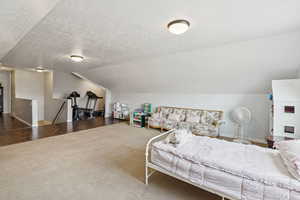 Carpeted bedroom with vaulted ceiling and a textured ceiling
