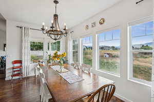 Dining room with a chandelier, plenty of natural light, and dark wood-type flooring