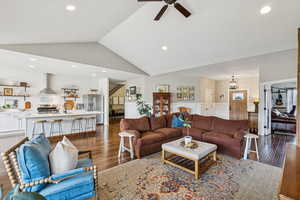 Living area with wainscoting, dark wood-style floors, a ceiling fan, vaulted ceiling, and recessed lighting