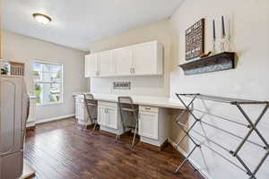 Home office featuring built in desk, washer / clothes dryer, and dark wood-style floors
