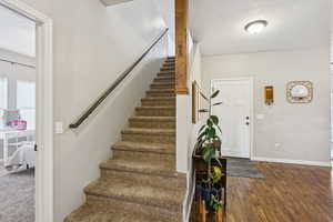 Stairs with wood finished floors and a textured ceiling