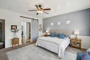 Bedroom with a barn door, carpet, and a ceiling fan