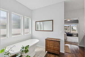 Full bathroom featuring a soaking tub and ceiling fan